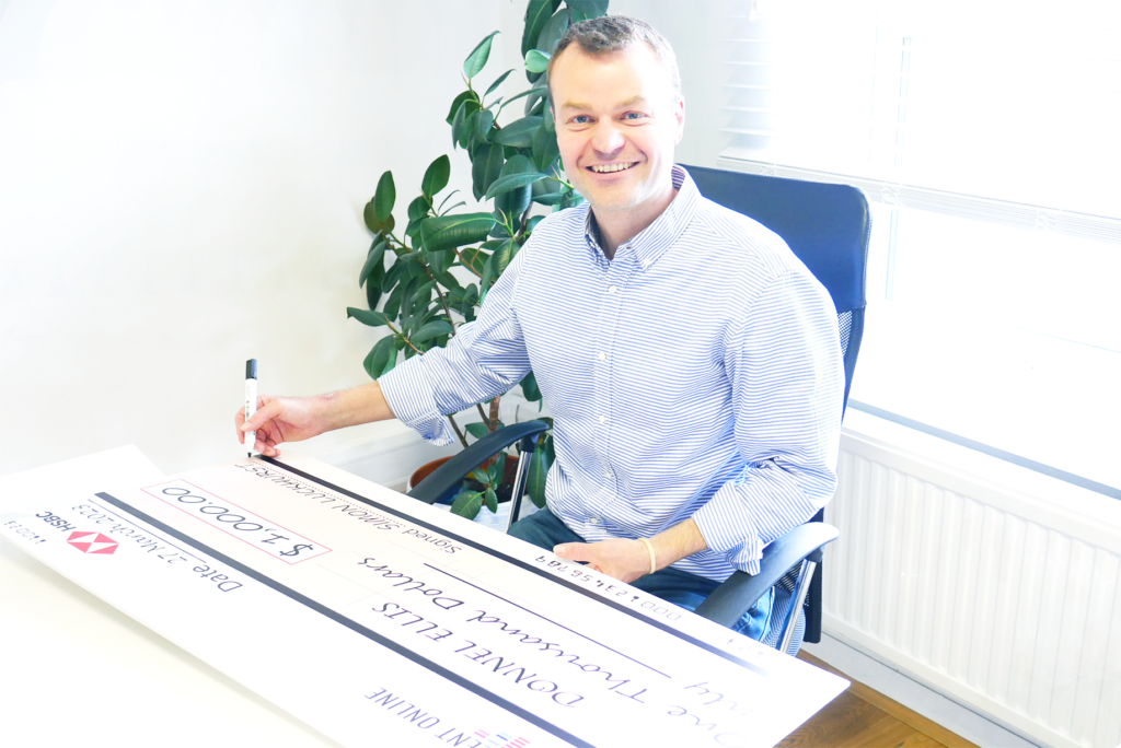 Simon Luckhurst signs a scholarship winner's cheque.